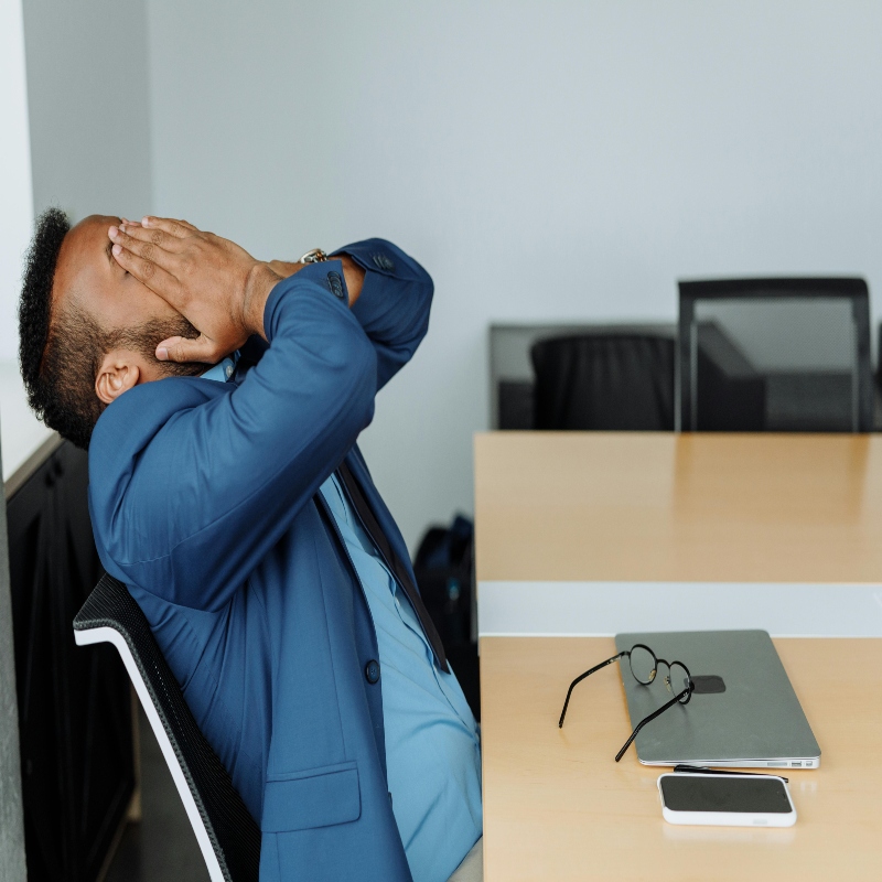 Male sitting at desk with hands covering face looking stressed