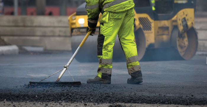 Operative wearing hi vis workwear resurfacing road