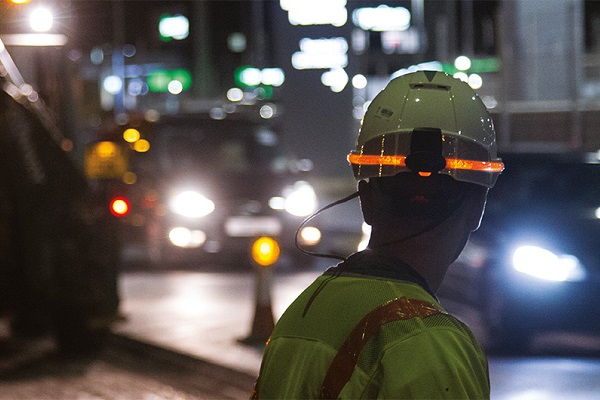 Operative working at night wearing additional hard hat illumination for safe working