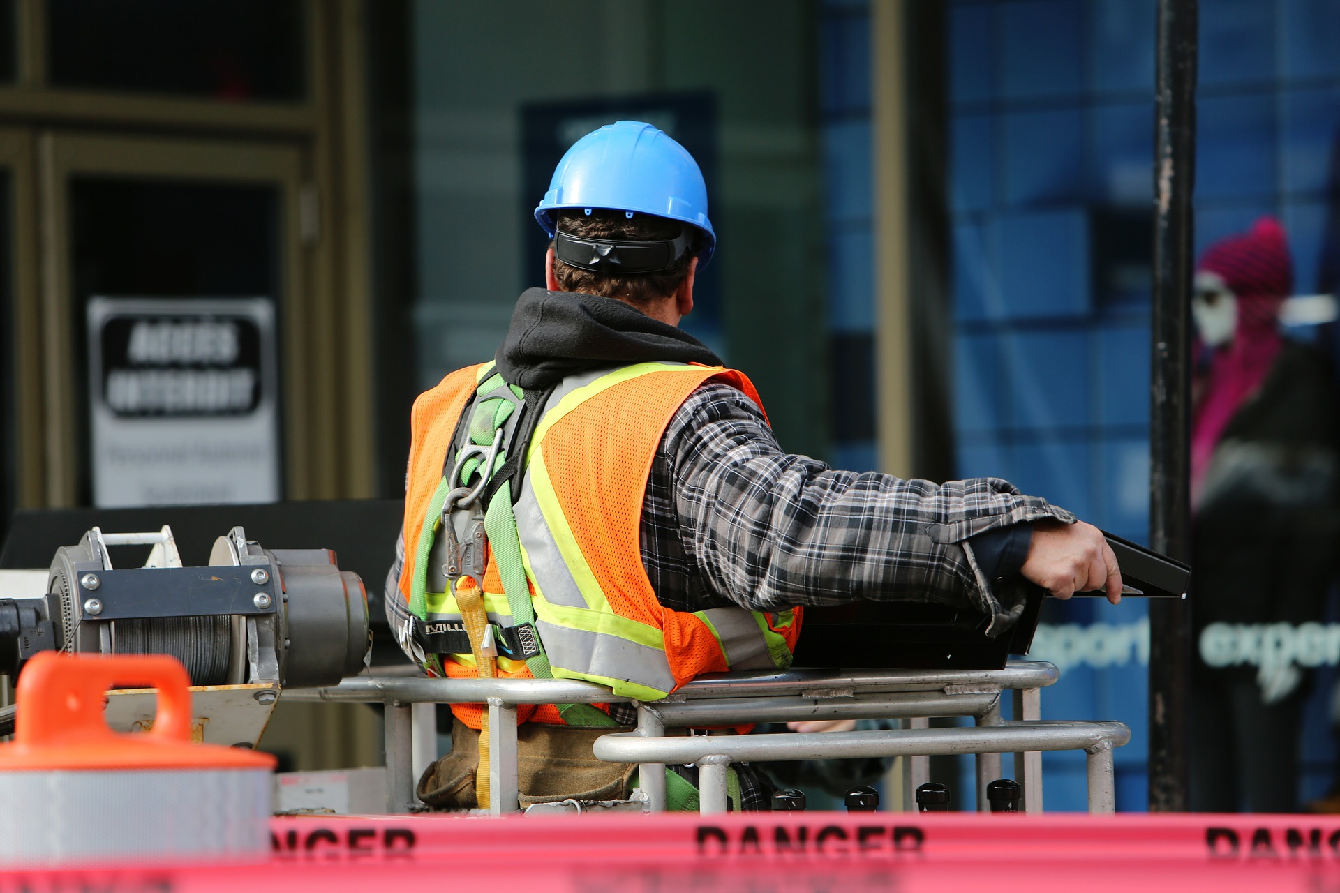 Construction contractor wearing hi-vis and blue hard hat operating machinery 