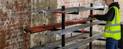 Construction worker standing by metal stand manually lifting site materials